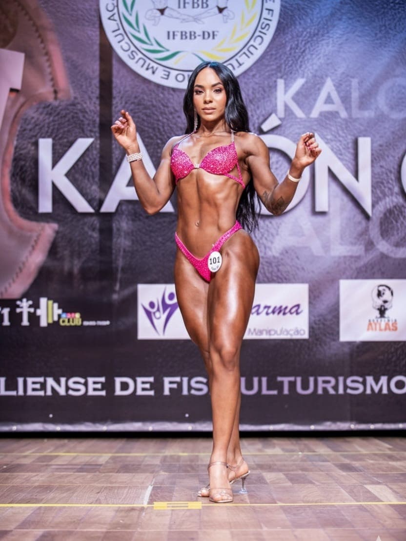 Janaína Fiit no palco, pose de fisiculturismo